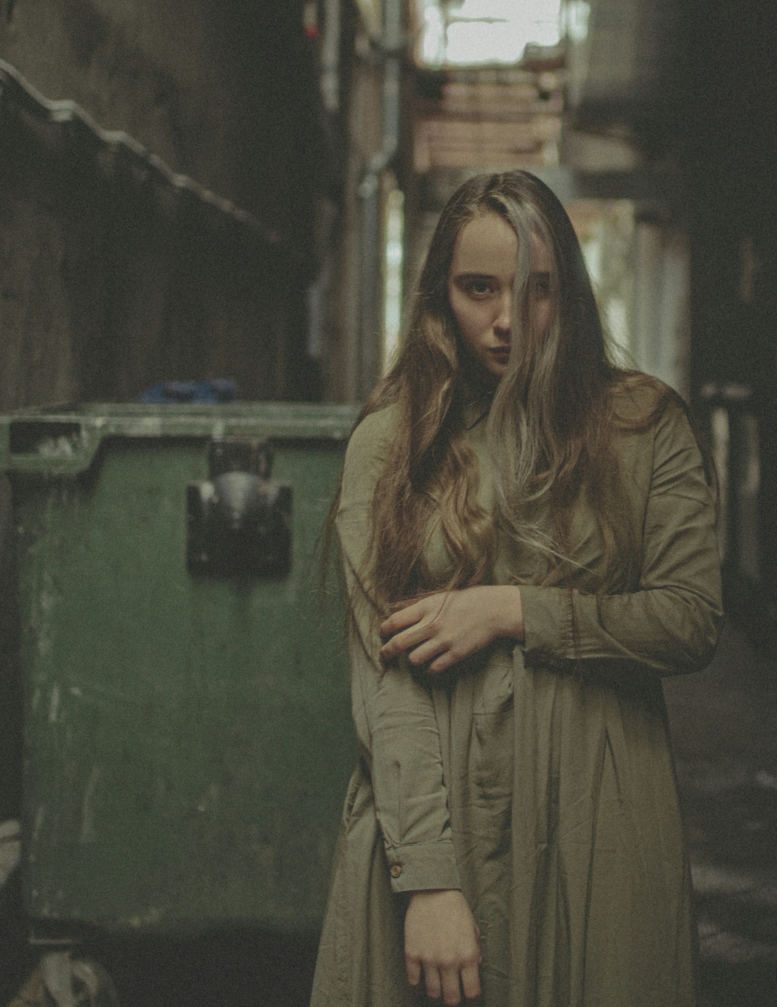 woman in brown coat standing near green wall